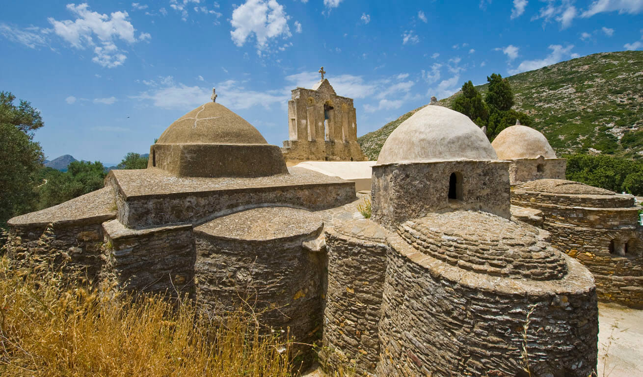 Stone Byzantine church with three small domes and a bell tower. 