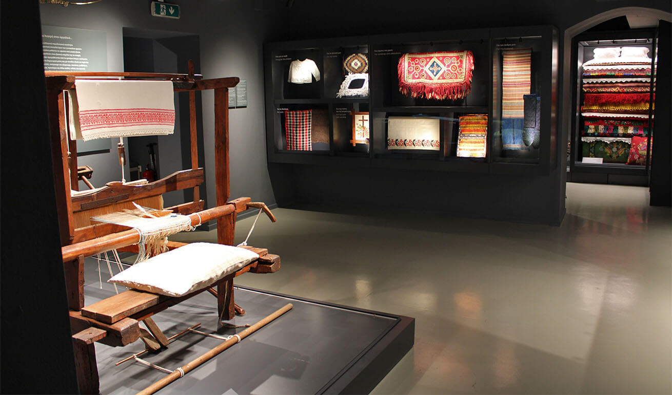 Museum interior with loom and display cases with woven items.