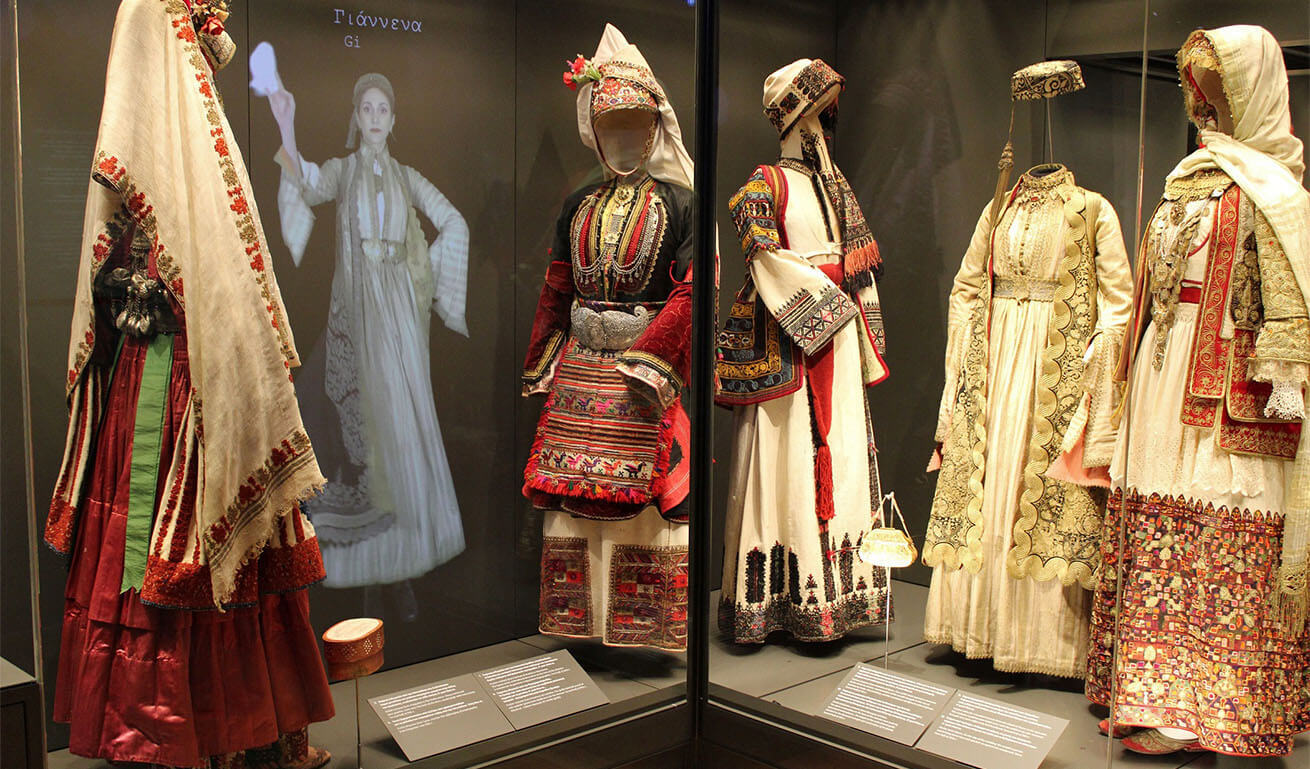 Large glass museum displays with traditional women's costumes.