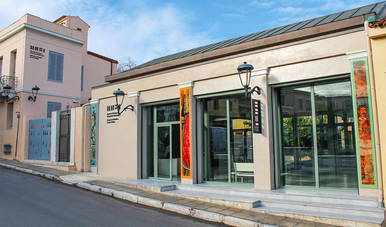 Traditional ground floor renovated building on a street with large glass doors and posters on the walls. Partly cloudy.