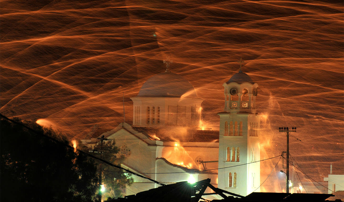 White church with dome and bell tower at night with fireworks.
