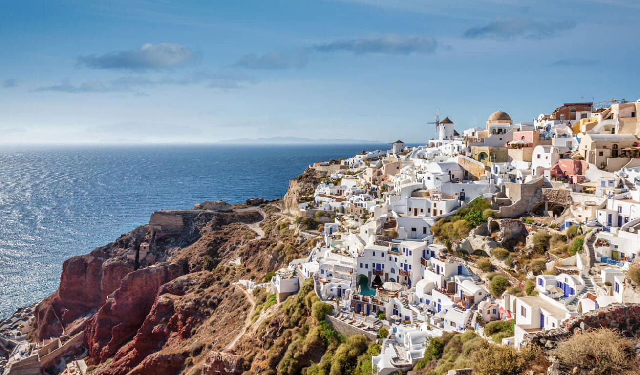 Picturesque Cycladic village on the rocks overlooking the sea, illuminated by the sun.