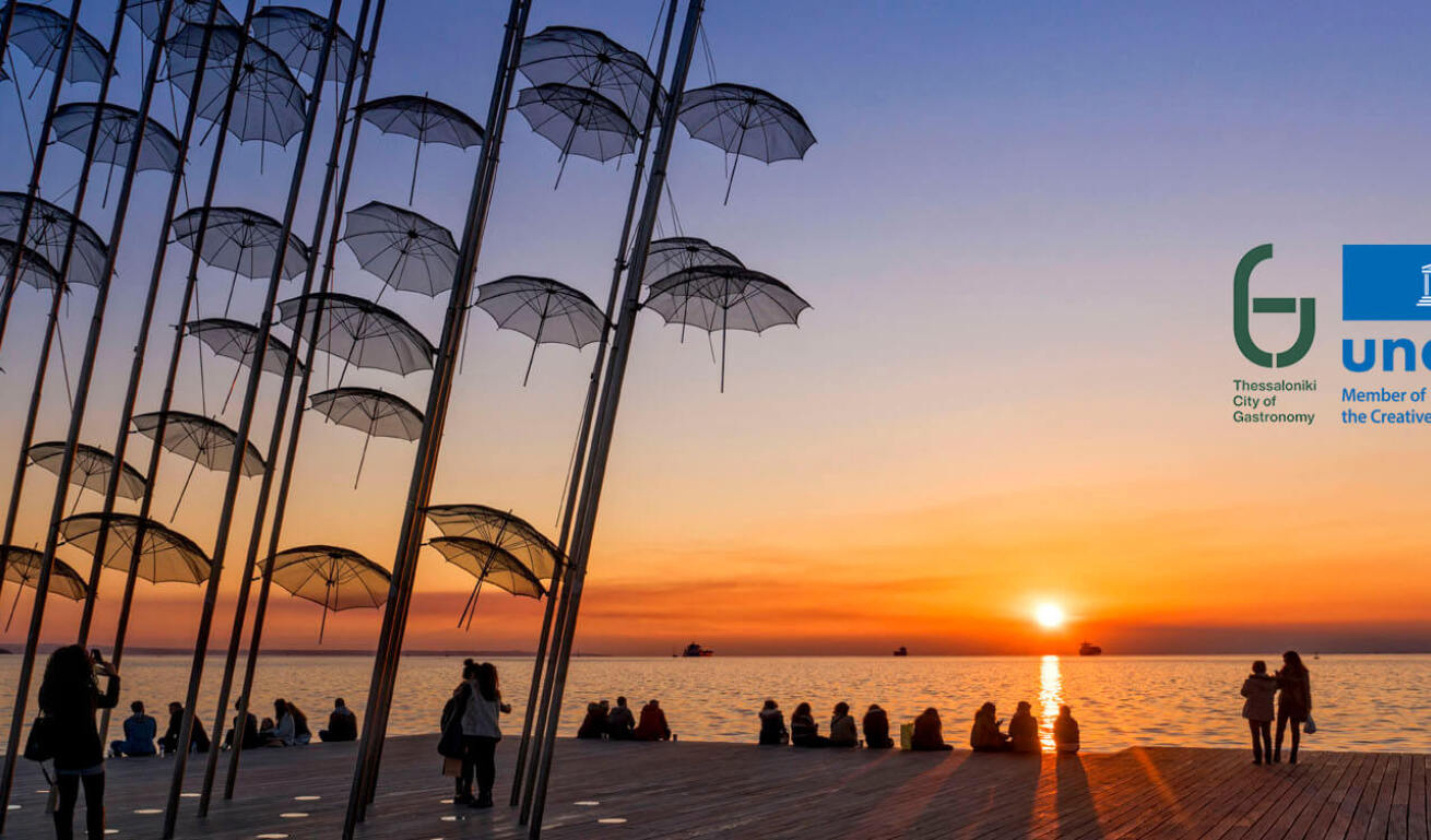 Άποψη της παραλίας της πόλης με πολλά άτομα να κοιτάζουν το ηλιοβασίλεμα