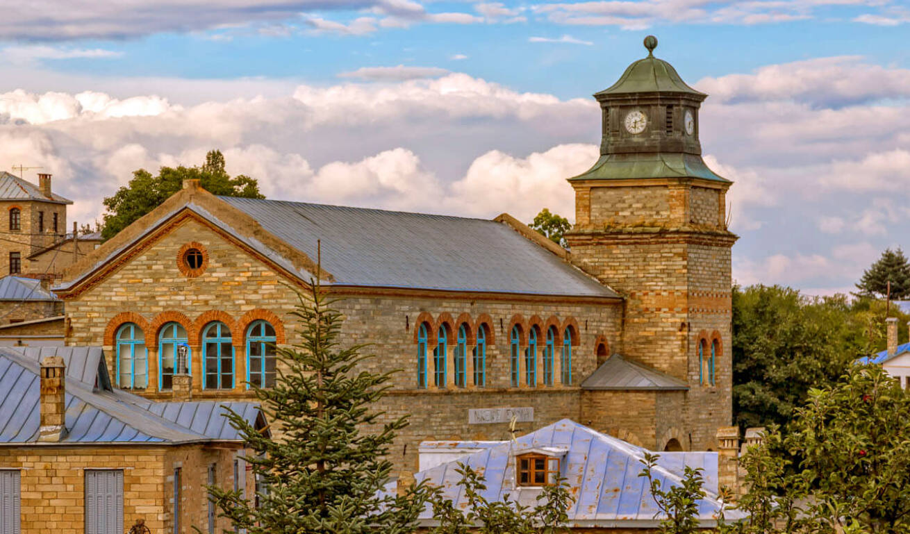 Παραδοσιακό πέτρινο κτίριο που περιβάλλεται από πολλά δένδρα