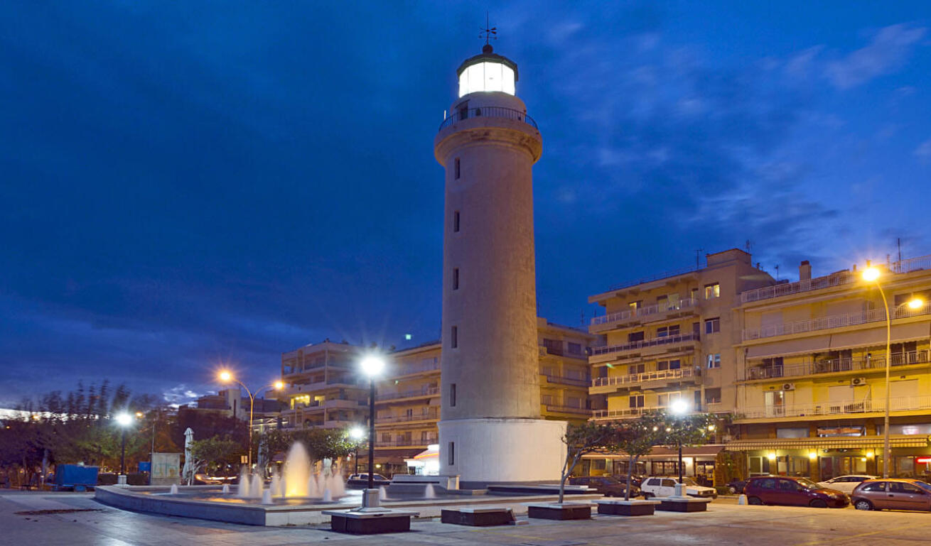 View of the illuminated port during dusk, with the lighthouse dominating at the area