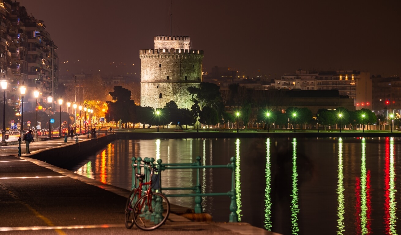 The white tower of thessaloniki as a background of the maritime promenade of Thessaloniki, at night time