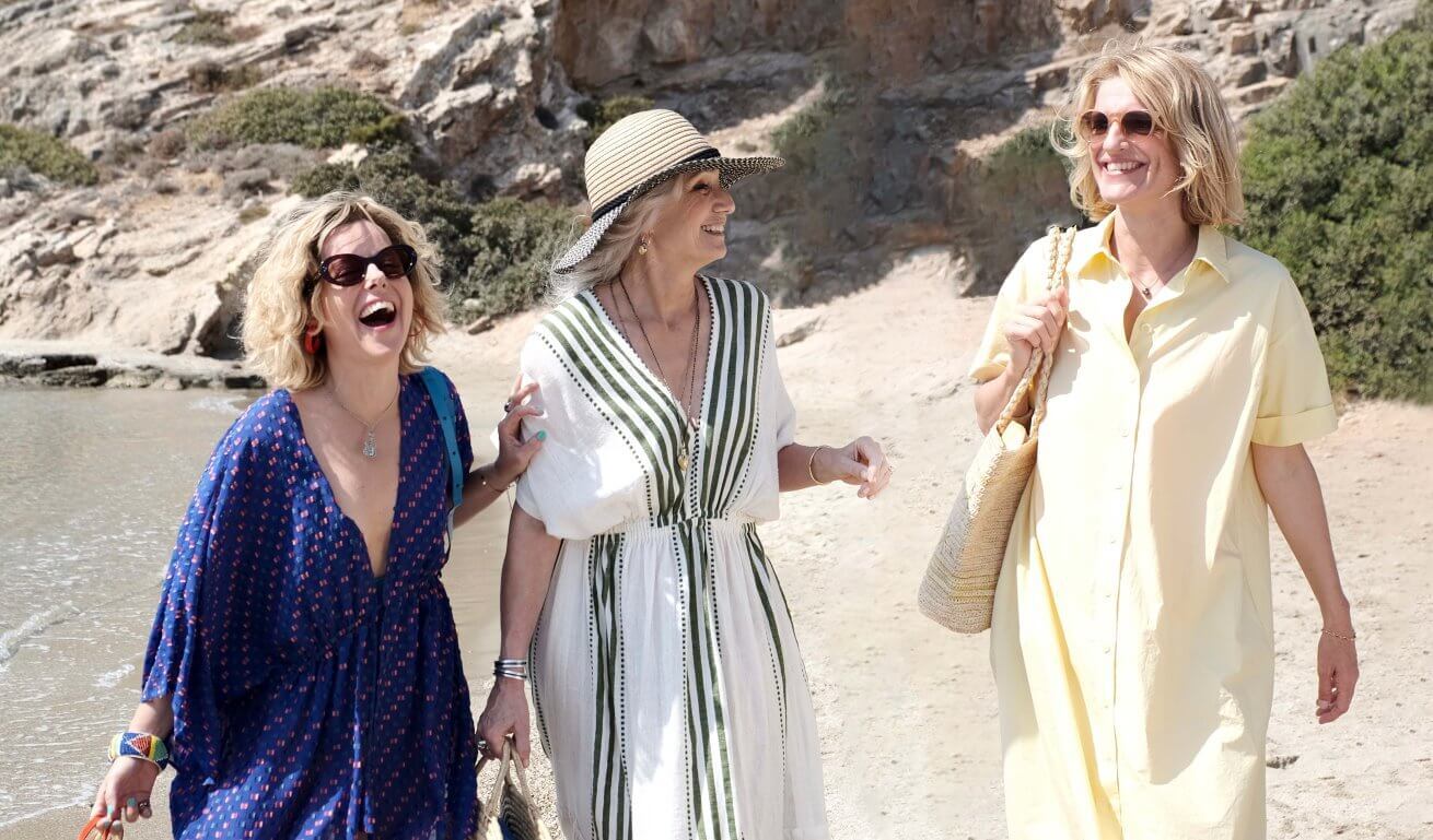 threww women laughing while walking at the beach