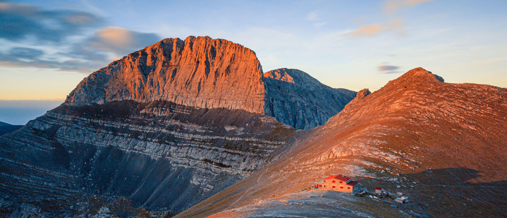 Rocky mountain top with a small shelter in the sunset.