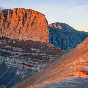 Rocky mountain top and closer a small shelter in the sunset light. 