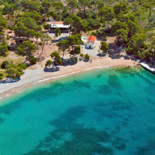 A beach with greenish blue waters and a small chapel