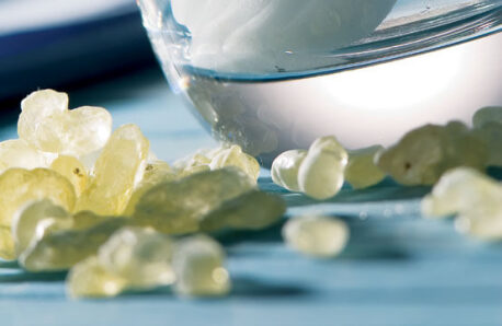 Transparent drops of mastic on a table in front of a glass. 