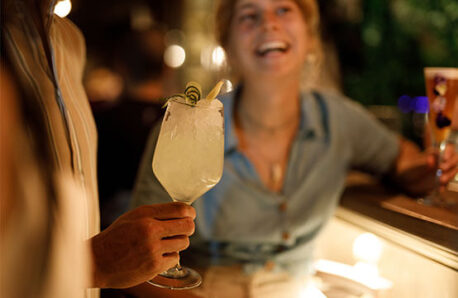 A woman laughs and has fun in the evening at an outdoor bar with drinks.