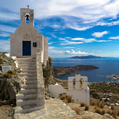2 small white churches with bell tower and harbor view 