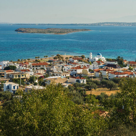 Παραθαλάσσιο χωριό με κεραμοσκεπές και μια ασπρη-γαλάζια εκκλησία να ατενίζει απέναντι μια βραχονισίδα.
