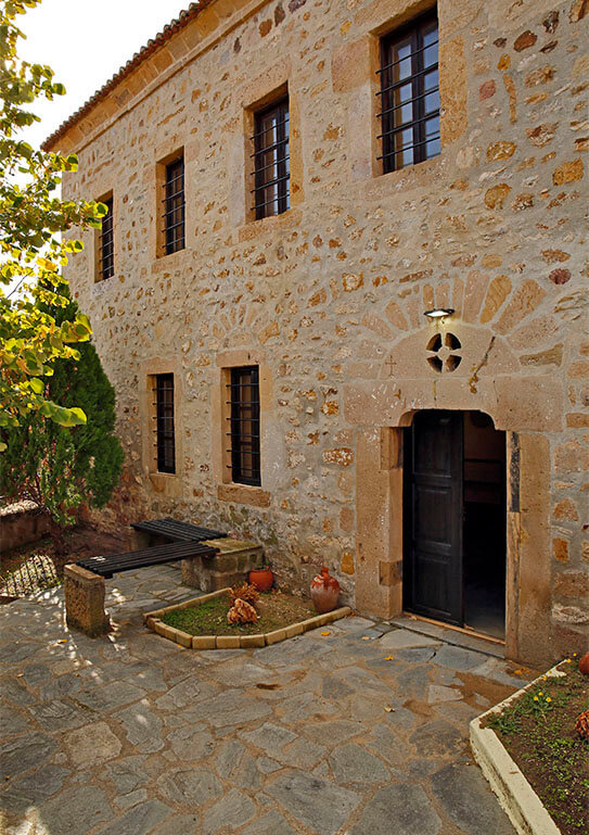 Two-story stone building with wooden door and stone-paved entrance.