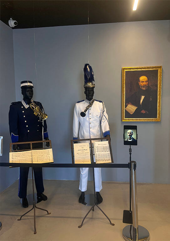 Museum room with full-length dolls in military uniforms, sheet music and a portrait painting on the wall.