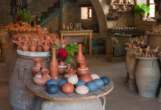 Εσωτερικός χώρος με πέτρινους τοίχους. Μεγάλα πήλινα πιθάρια που πάνω τους υπάρχουν πολλά μικρά πήλινα αντικείμενα.