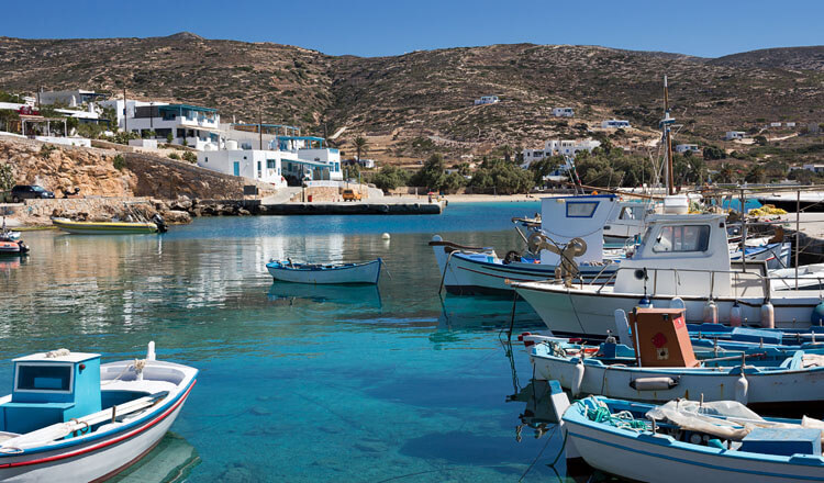 Small port with small boats. In the background a few houses and a beach. 
