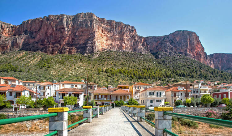 Άποψη του Λεωνίδιου με τα παραδοσιακά σπίτια, που το περιβάλλουν δέντρα και απότομοι ογκώδεις βράχοι