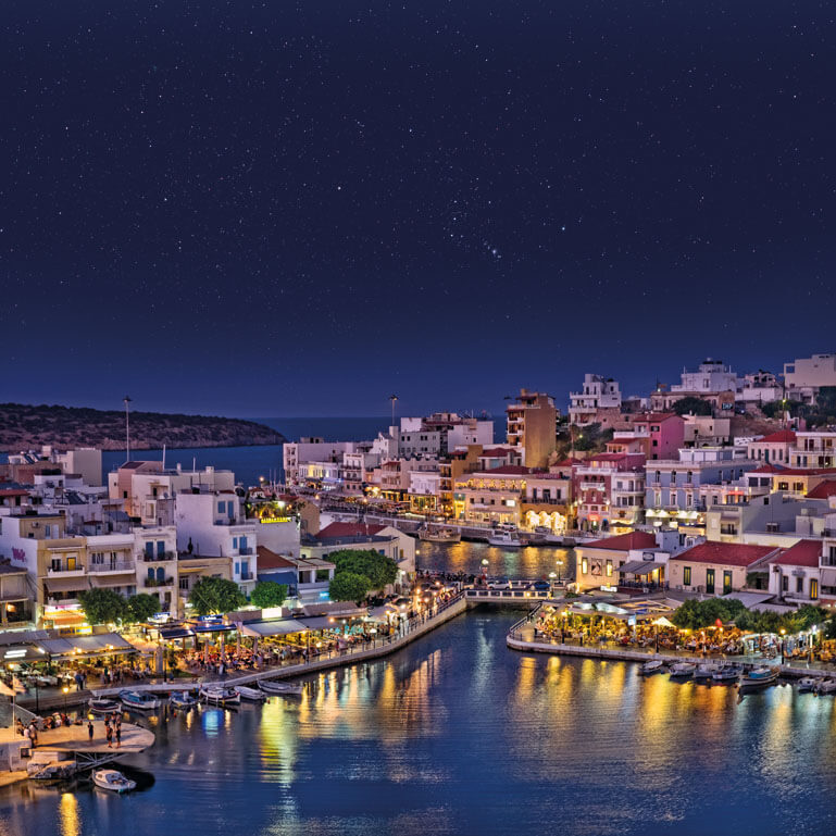 Panoramic view of the town of Agios Nikolaos, with the traditional houses and the illuminated port at night