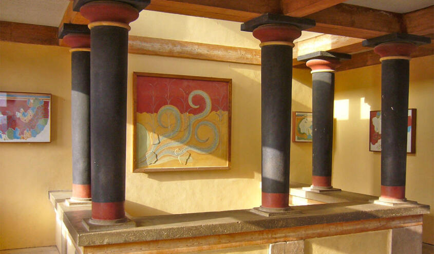 Interior of a historic building featuring Minoan columns and ancient frescoes on the walls.