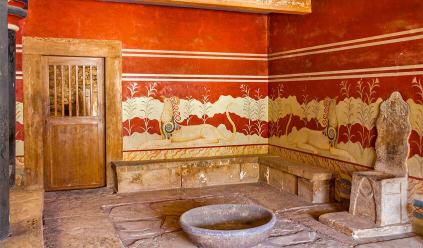 Interior of an ancient building with frescoes. Old wooden door on one side and marble throne on the other.