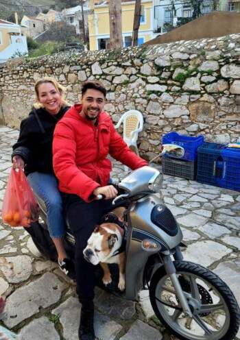 the authors of the book (a man and a woman) riding a scooter with shopping bags and a small dog