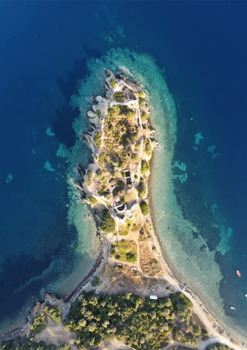 Aerial view featuring a small, narrow piece of land with a few buildings surrounded by clear blue waters.