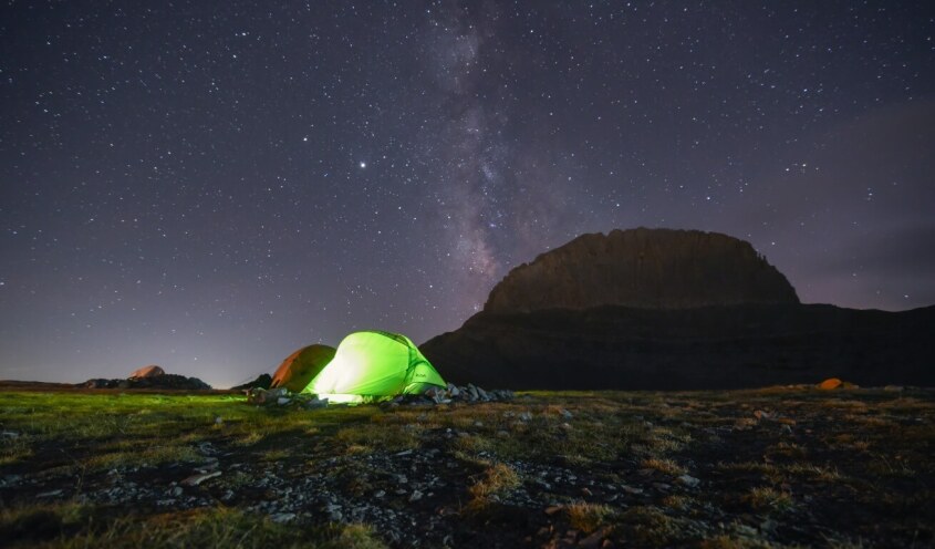 Two tents camping at mountain olympus at nighttime, sky is full of stars