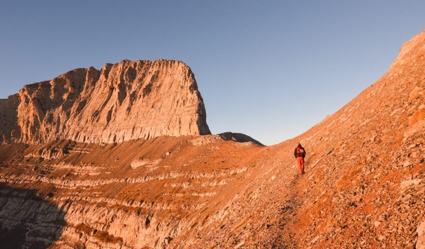 a man walking on olympus mountain at sunrise