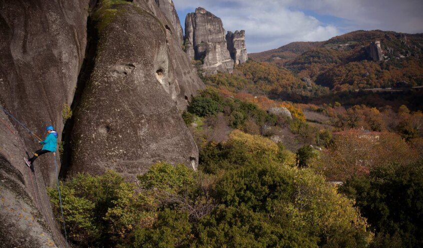 View of meteora rocks with a woman climbing in the background