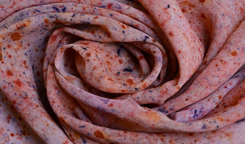 Close-up of a swirled fabric with a speckled pattern in shades of orange, blue, and purple