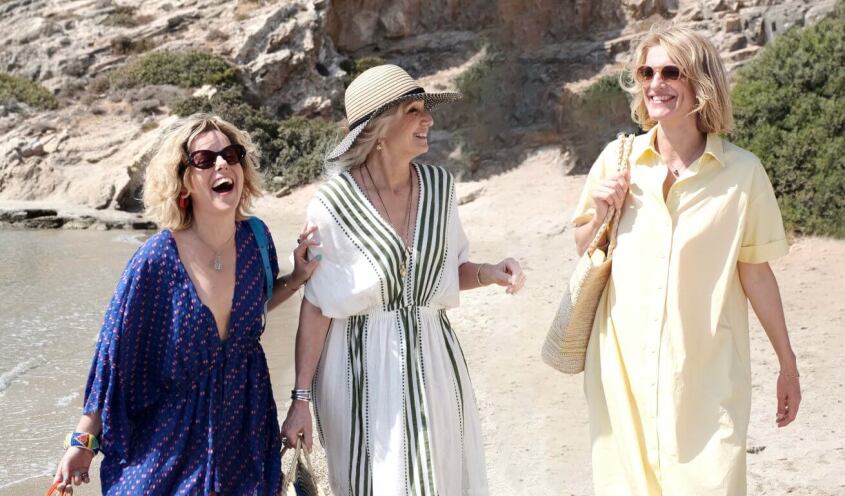threww women laughing while walking at the beach